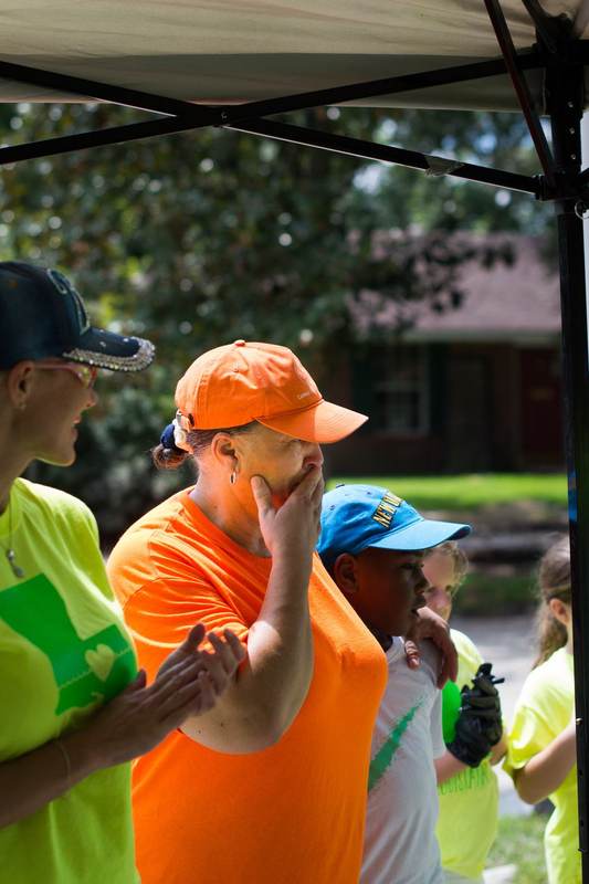 A child in an orange vest with volunteers.