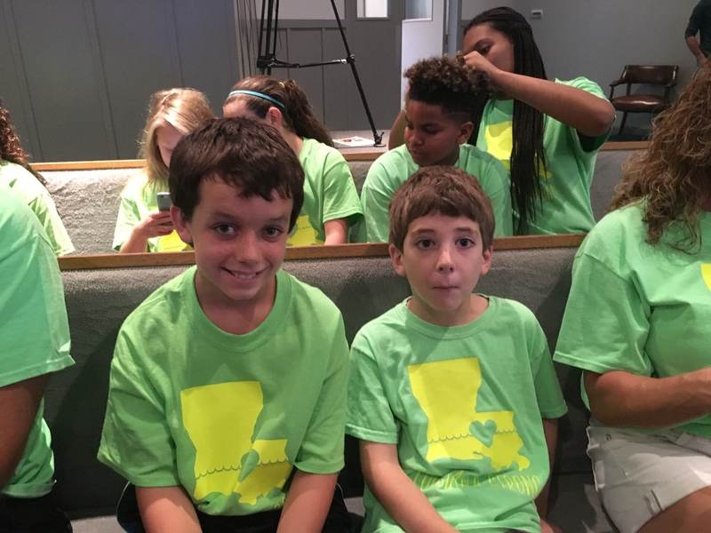 Children in green shirts seated together.