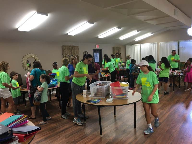 Volunteers at supply tables in a community room.