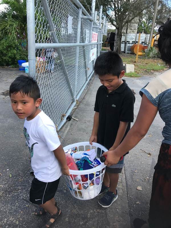 Two boys carrying a laundry basket of clothes.