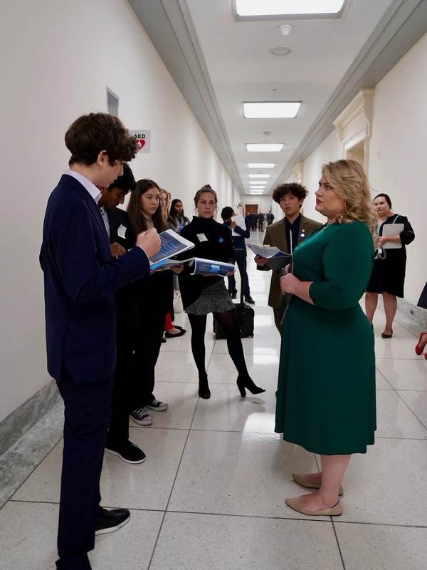 A student speaking with an official in a Capitol hallway.