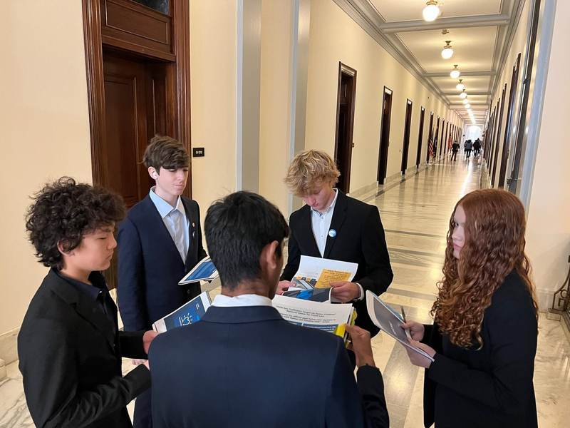 Students talking with an adult in a Capitol hallway.