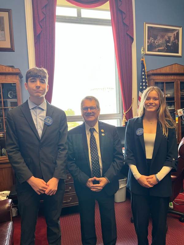 Students with an official in a wood-paneled office.