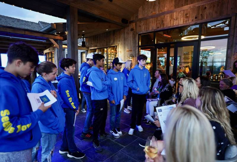 See Us Now members in blue hoodies outside a restaurant.